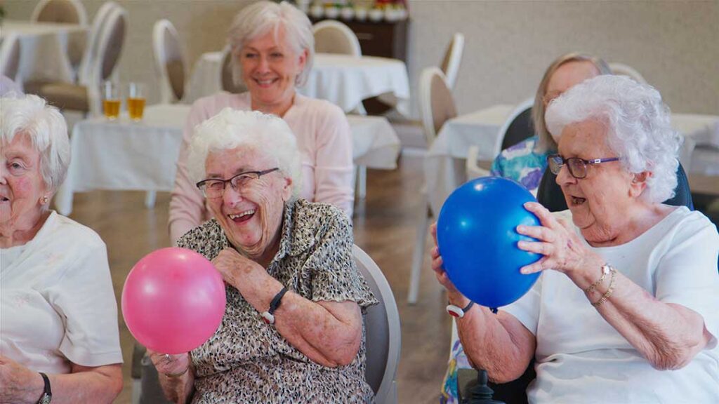 Family member sits beside an assisted living resident with a hospice nurse reviewing a comfort-care plan.